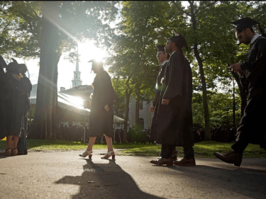 Students in graduation outfits walking in Harvard Yard