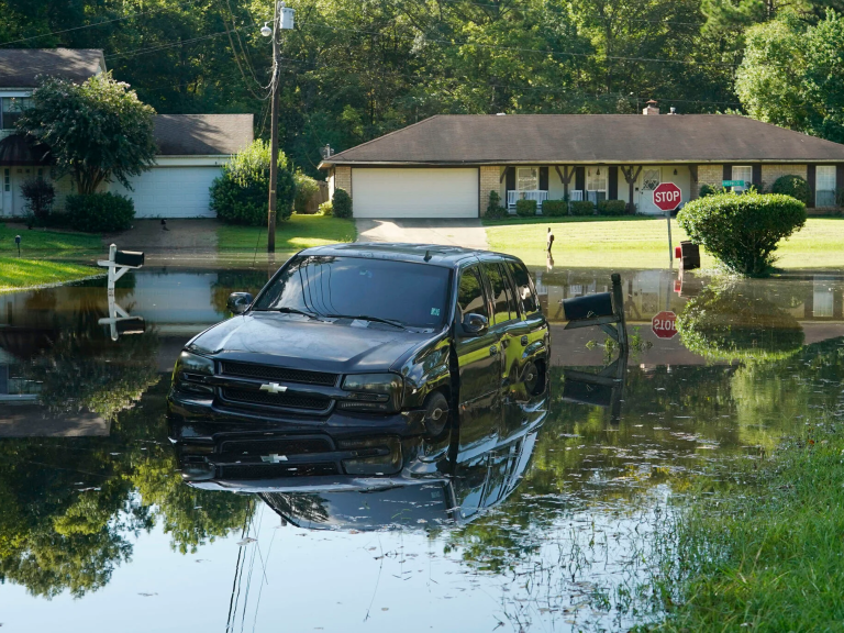 A car submerged in water on a flooded suburban street