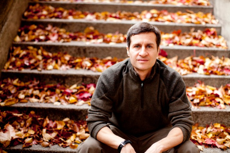 Man sitting on stairs covered with orange and gold leaves.