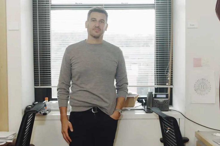 Man standing at a lab window looking at the camera.