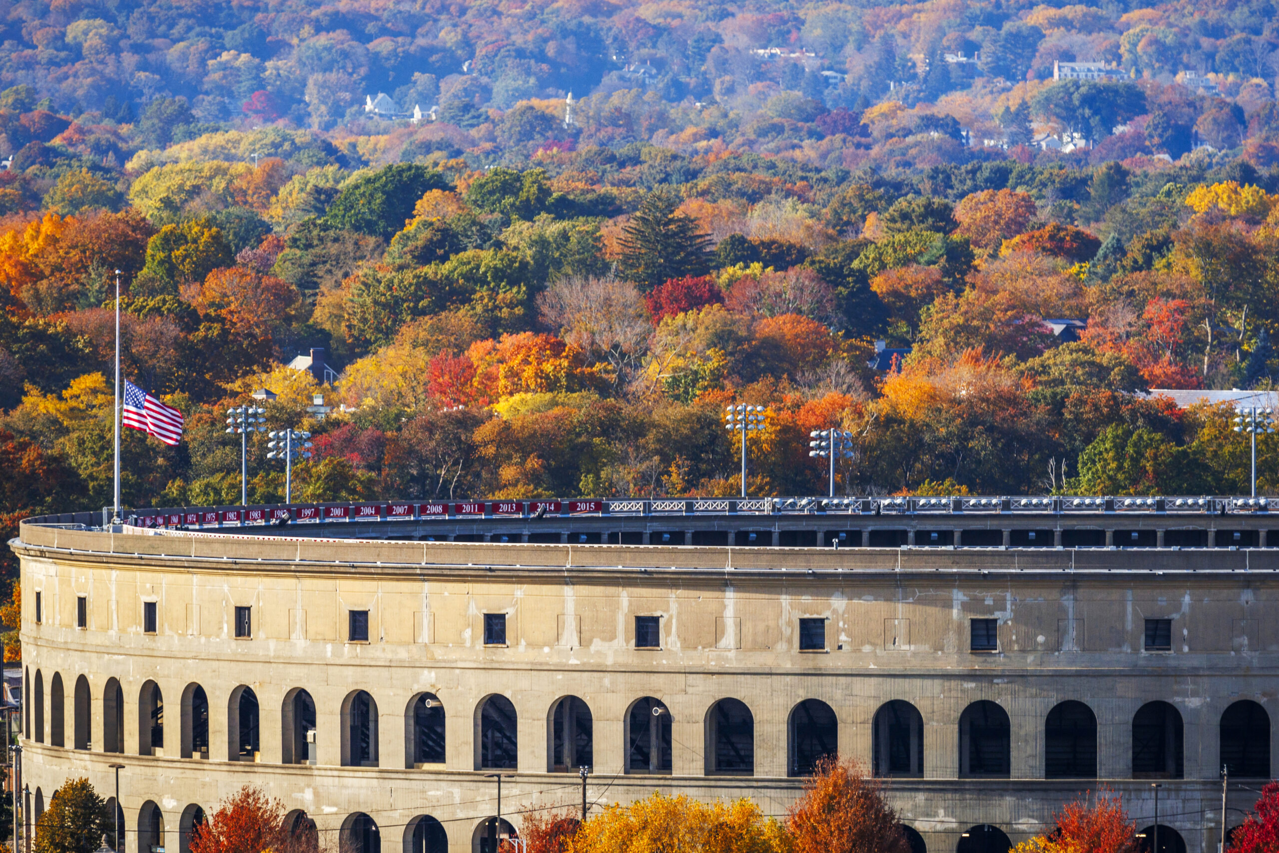 The Harvard colosseum with fall foliage behind it.