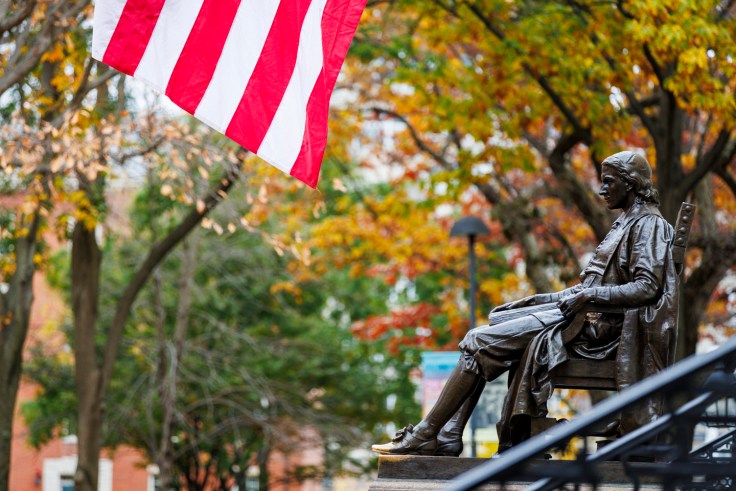 The John Harvard Statue with an American flag