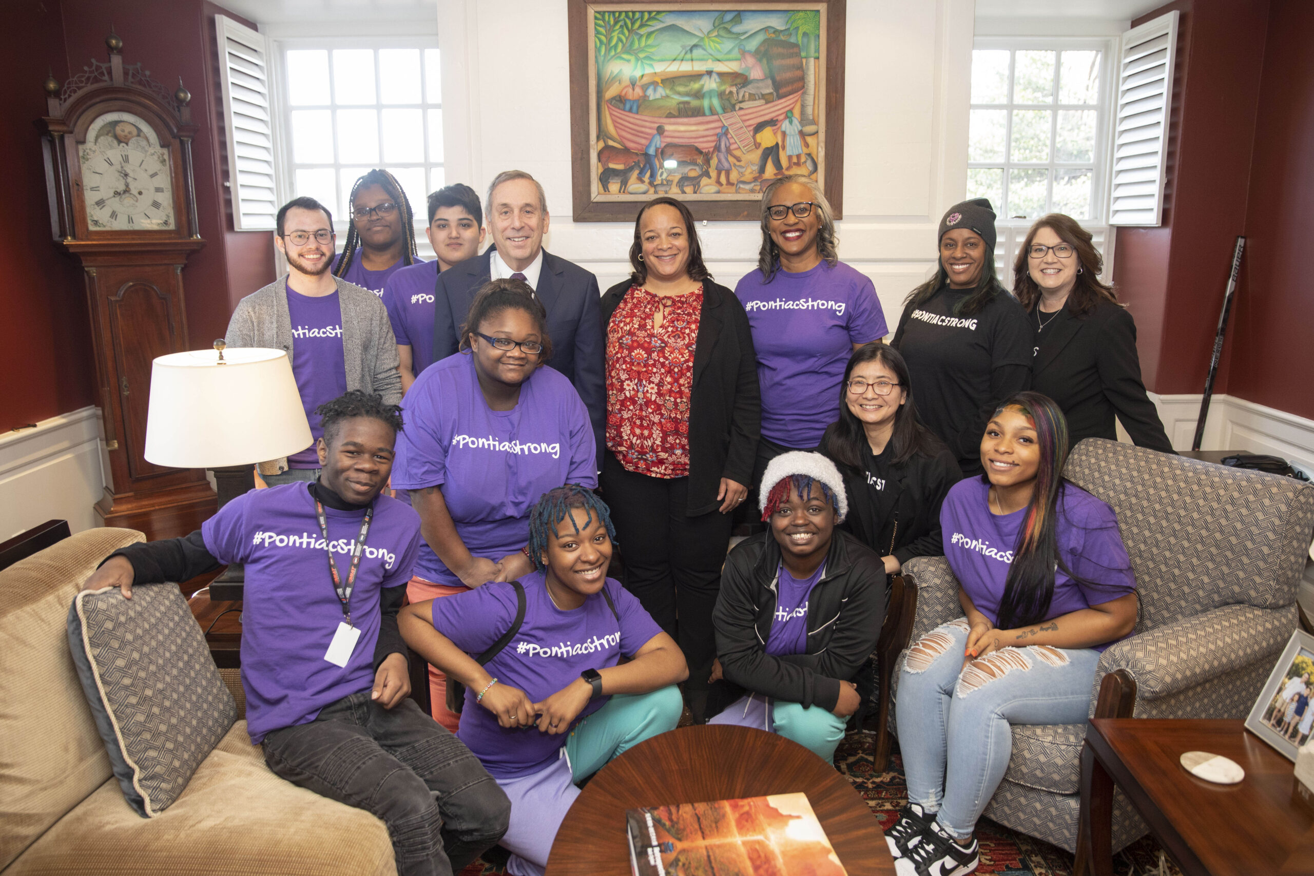 Students in purple shirts pose for a picture with Larry.