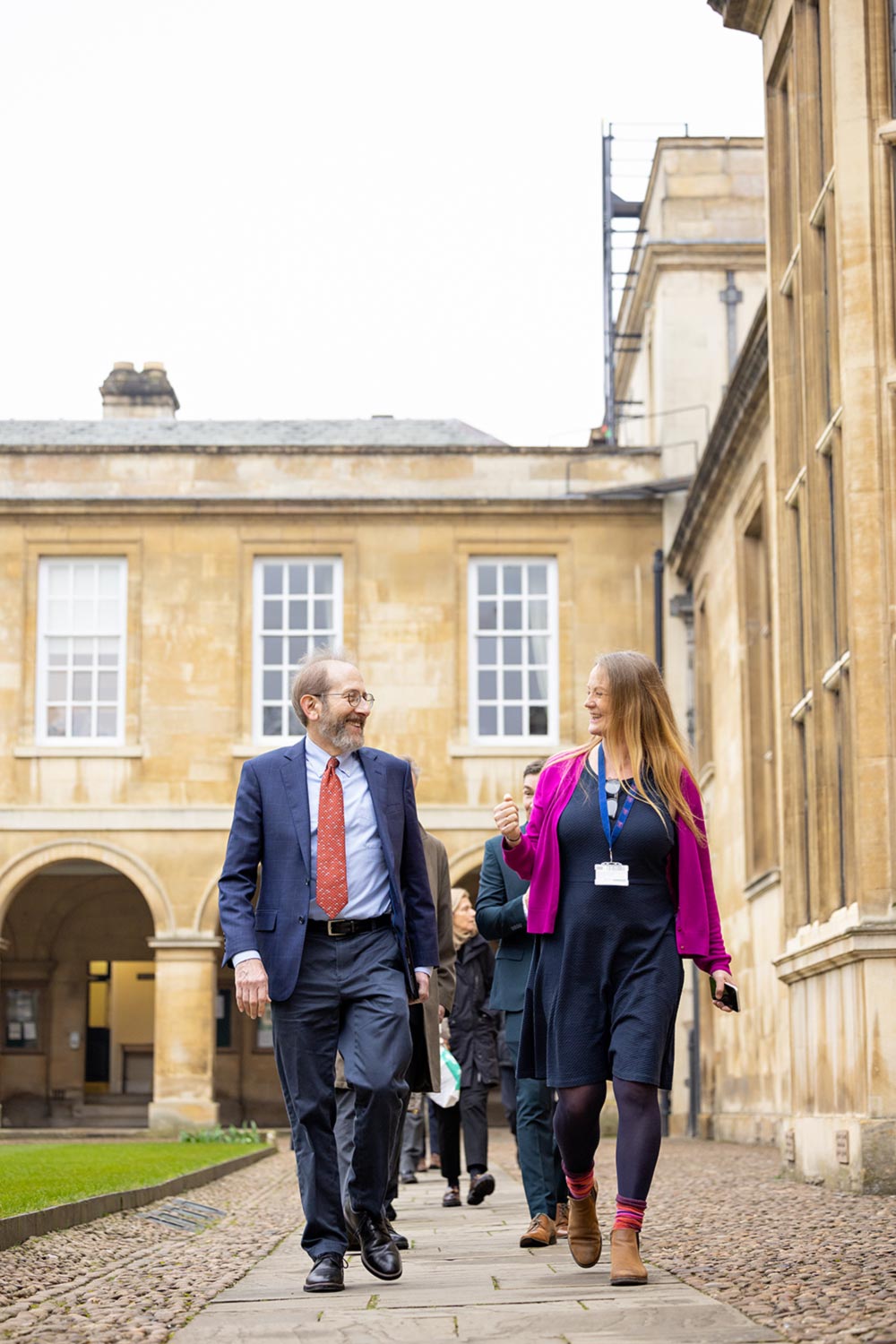 President Garber smiles at a tour guide. The two are walking in a courtyard.