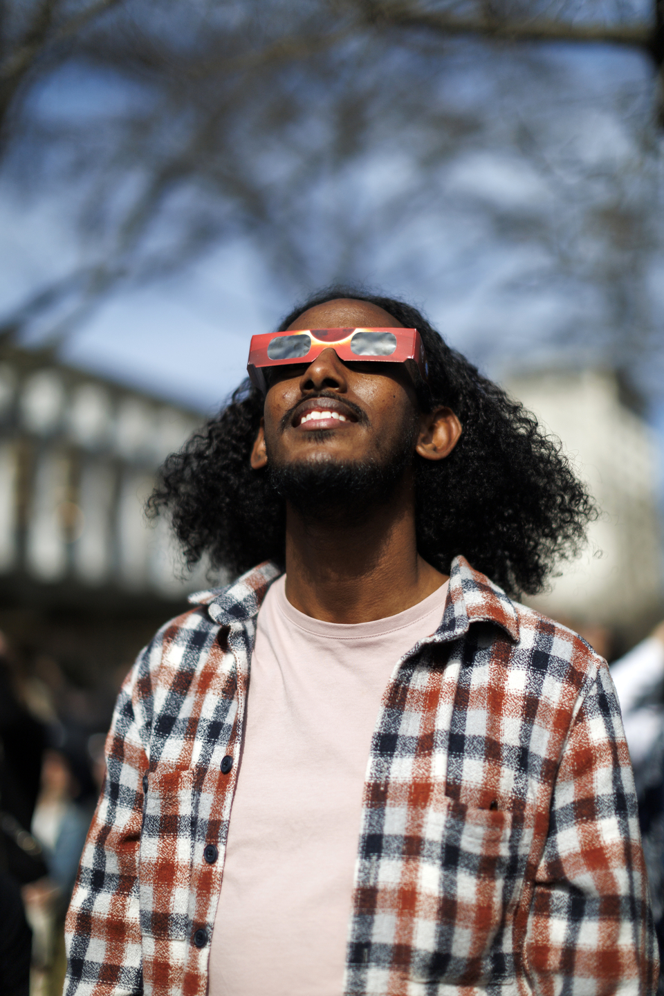 A man wearing solar glasses looks skyward.