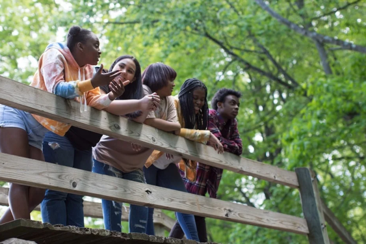 Five people leaning on a fence in the woods