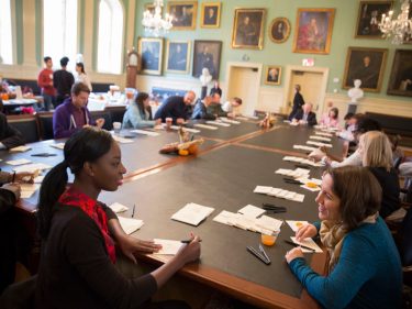 Colleagues around a table with pens and paper to make thank you cards.