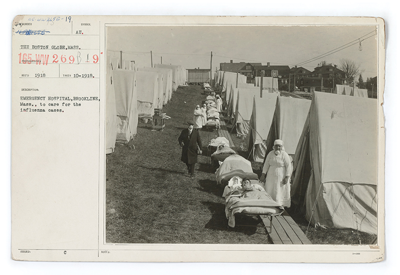 Image from 1918 of flu tents set up with patients in beds set up in front of them.