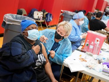 woman administering vaccine to a patient.