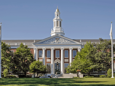 The facade of Baker Library against a bright blue sky.