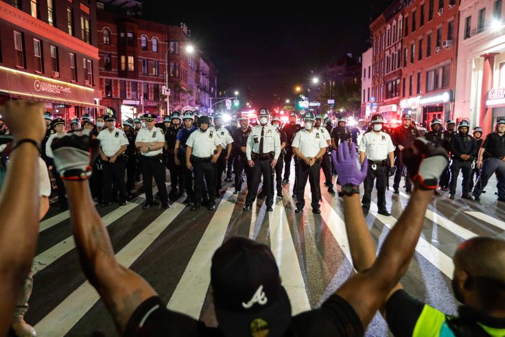 a line of police approaching people with their hands up