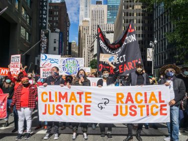 A group of protesters with a sign that says climate justice is racial justice