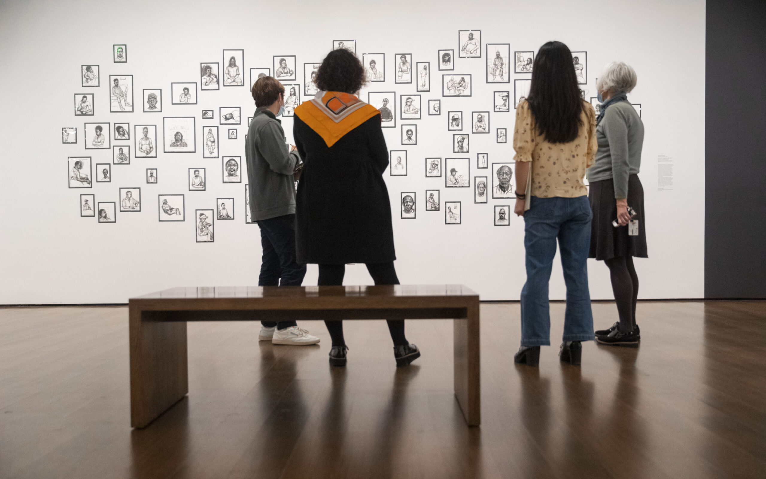 people looking at paintings on a wall