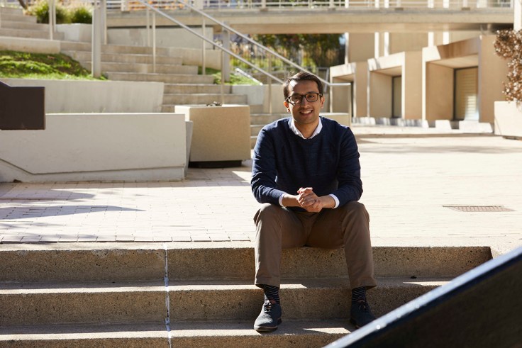 A young man sits on a set of stairs outside