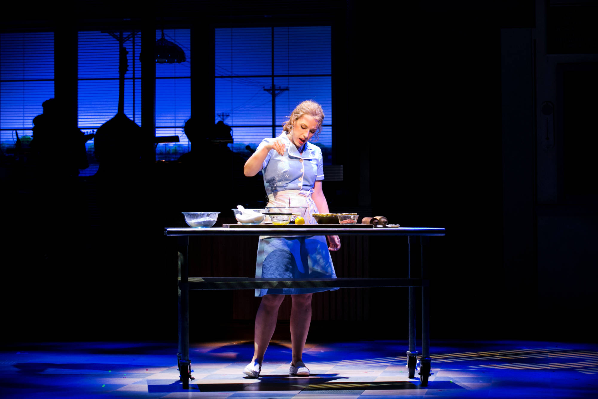 An actor dressed as a waitress performs on stage