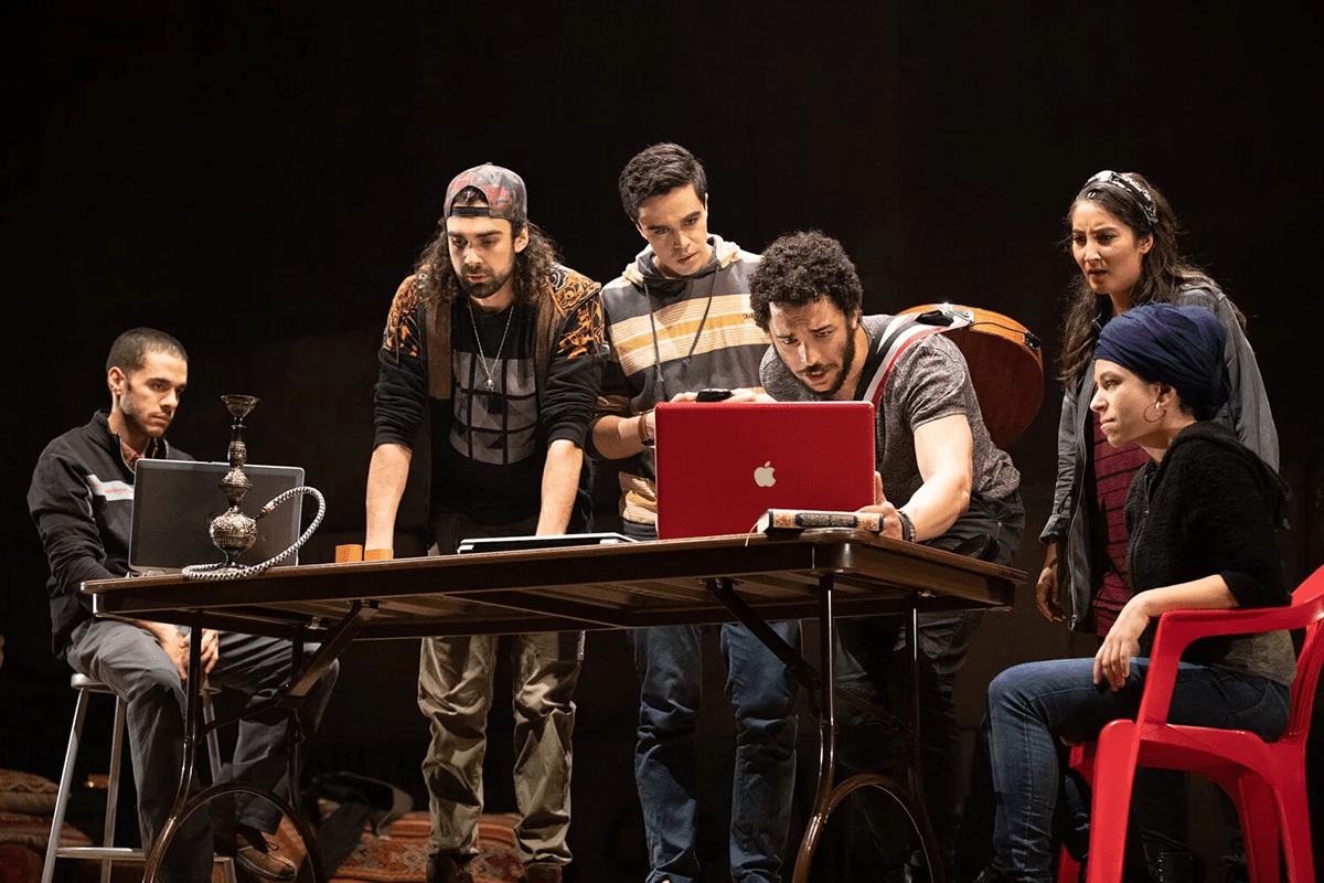 A group of actors and producers gather around a table preparing for a production