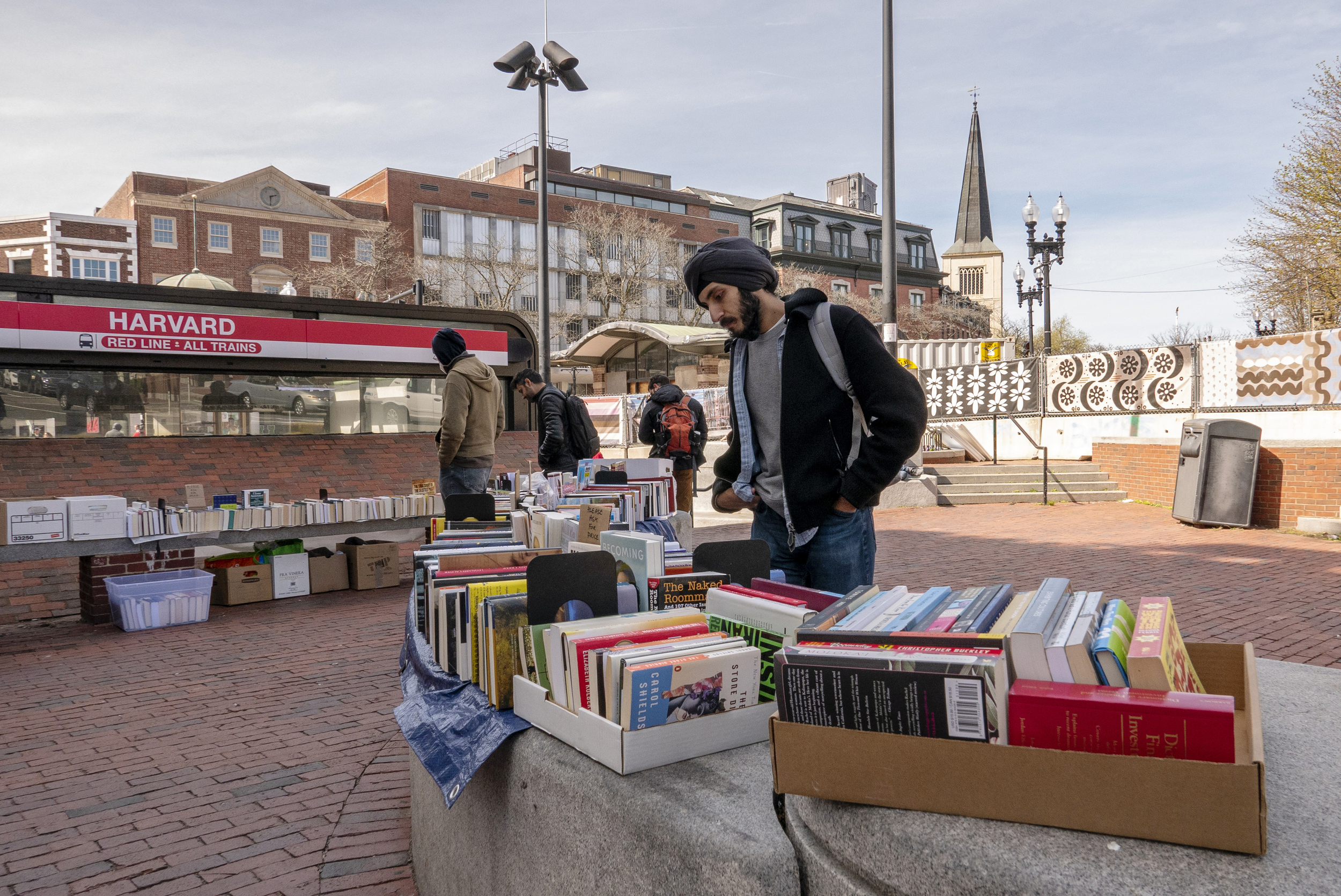 A man looks at boxes of books outside of the Harvard Square MBTA stop