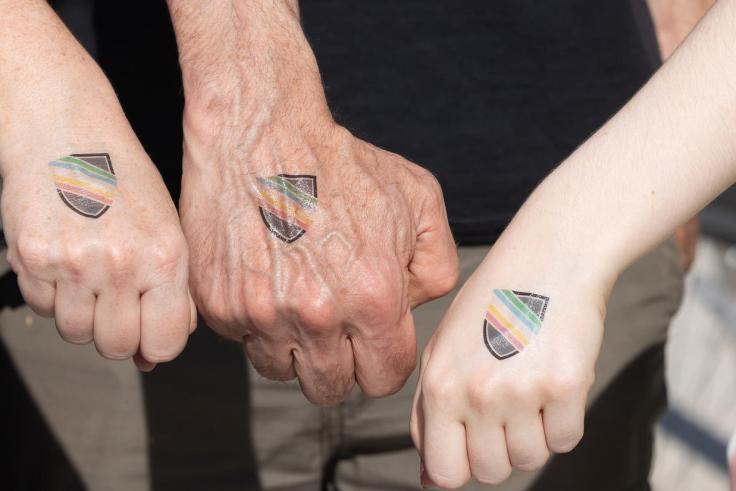 Three hands with temporary UDR logo tattoos on them