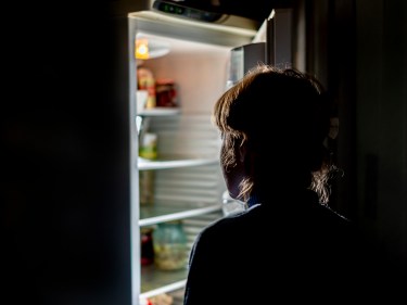 A person looking into a fridge at night