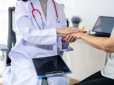 A doctor holding a patients hand