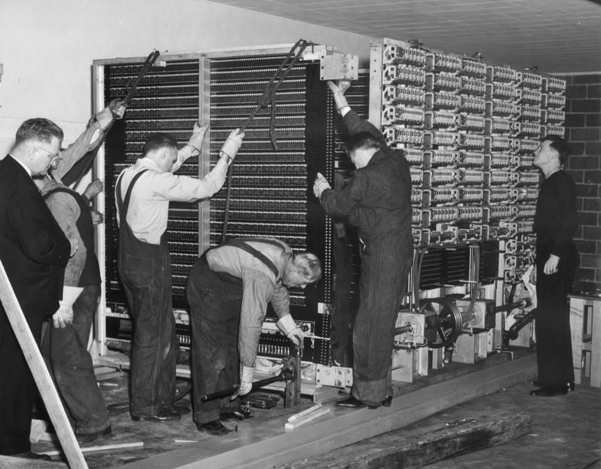 an old photo of people putting together a giant computer