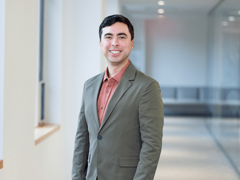 Adam Delgado poses in a gray blazer.