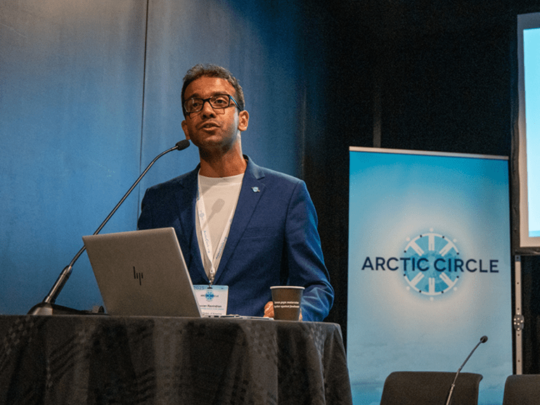 Bhuvan Ravindran stands at a podium giving a presentation on research.