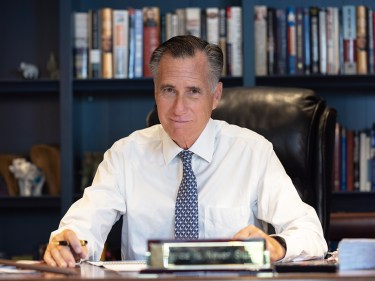 Mitt Romney sits at a desk.
